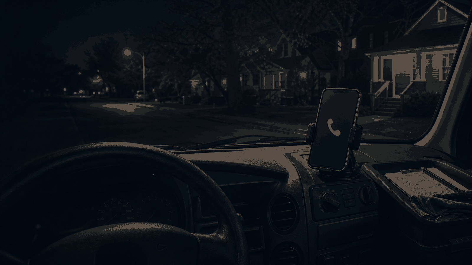 A work van dashboard at night beside a phone showing a missed call